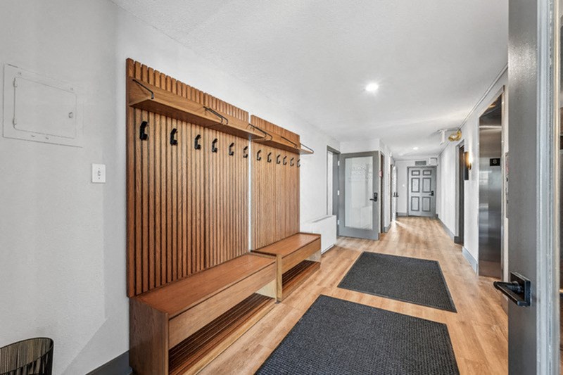 A long hallway with a bench and a door at the end. at The Lex At Lowry, Denver, 80224