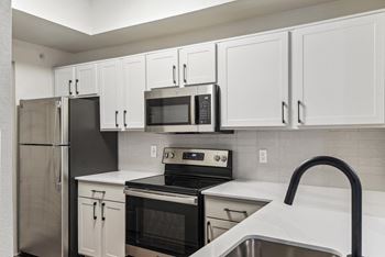 A kitchen with white cabinets and black appliances.at Onyx183, Austin, TX  