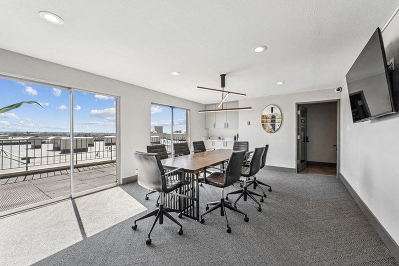 A conference room with a table, chairs, and a television. at The Lex At Lowry, Denver, CO