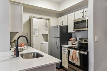 A kitchen with a black refrigerator and white countertops.at Onyx183, Austin  