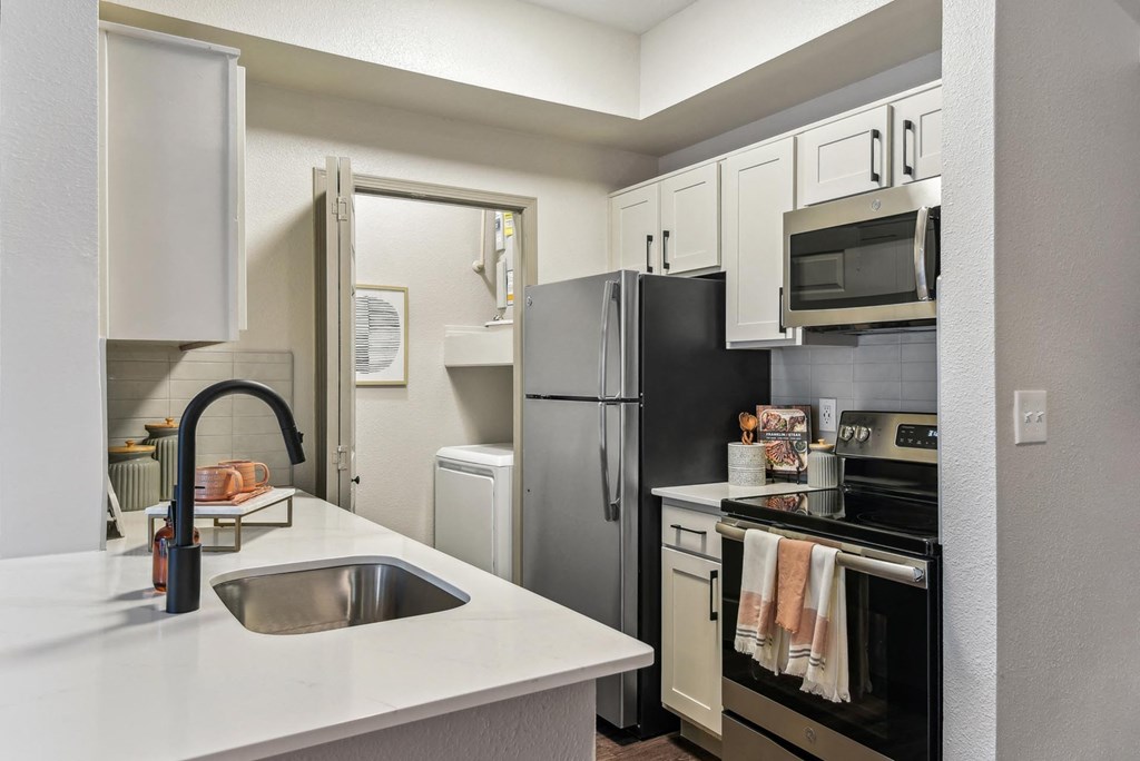 A kitchen with a black refrigerator and white countertops. A kitchen with a black refrigerator and white countertops.at Onyx183, Austin, TX