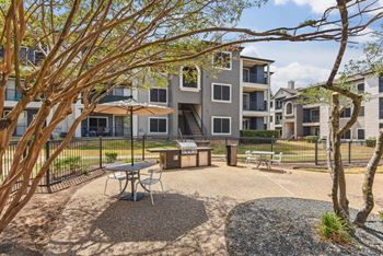 A courtyard with a picnic table surrounded by trees and apartment buildings.at Onyx183, Austin  