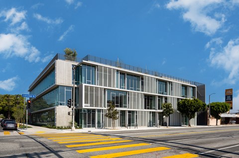 A modern building with a glass facade and a yellow crosswalk in front.