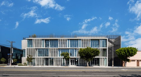 A modern building with a glass facade and trees in front.