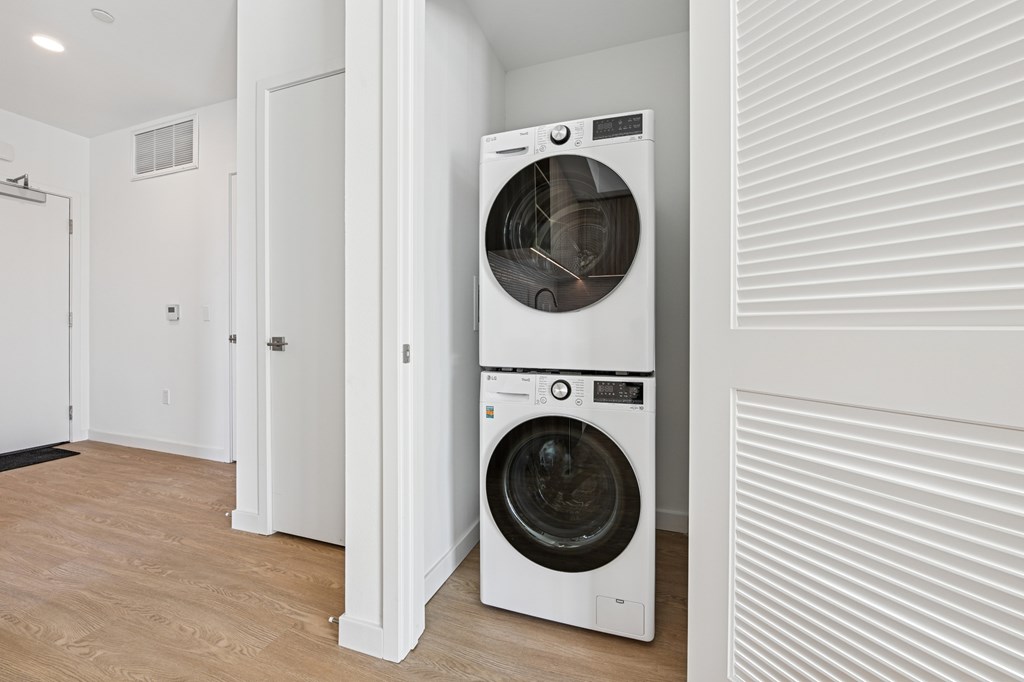 A white washing machine is in a laundry room at Coro Apartments, Los Angeles