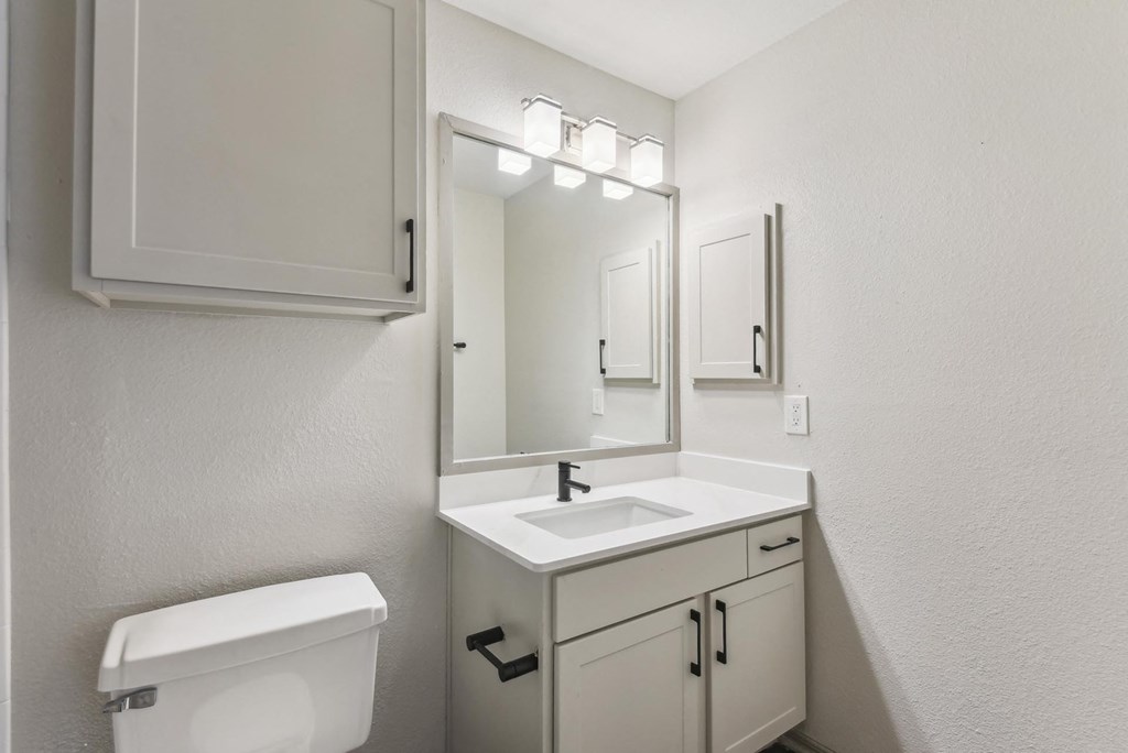 A white bathroom with a toilet, sink, and mirror. A white bathroom with a toilet, sink, and mirror.at Onyx183, Austin Texas
