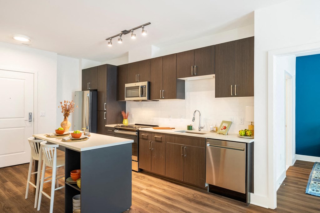 A modern kitchen with a white countertop and dark brown cabinets.at The Vale at the Parks, Washington, 20012  