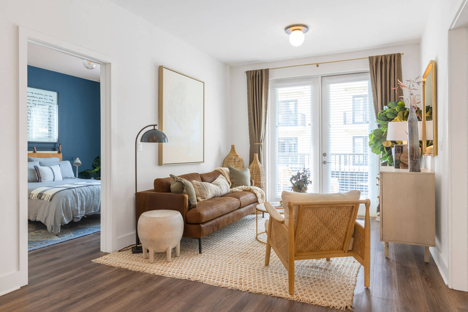 A living room with a brown leather couch and a white ottoman.