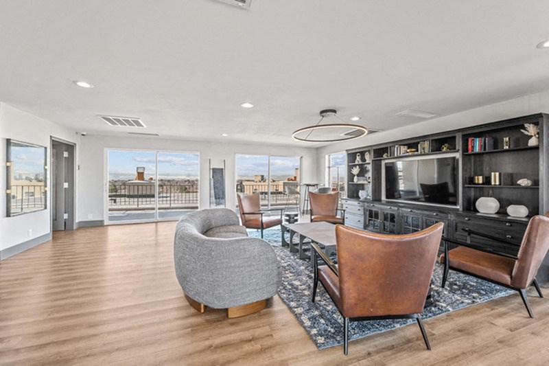 A modern living room with a grey chair and brown leather chairs. at The Lex At Lowry, Denver