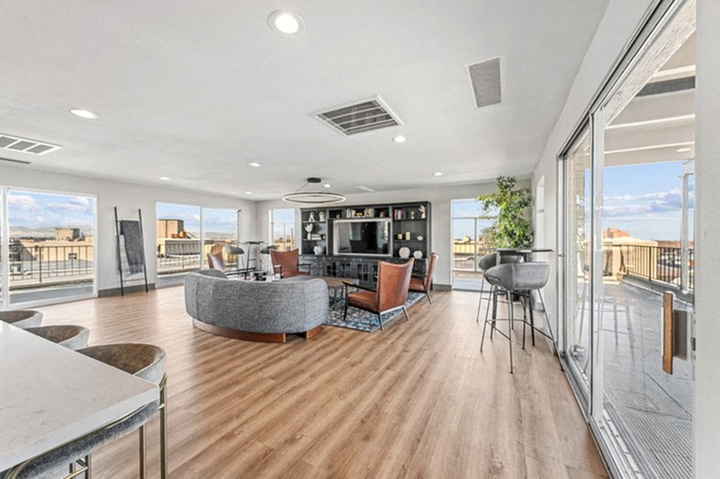 A modern living room with a curved sofa and a television. at The Lex At Lowry, Denver, CO