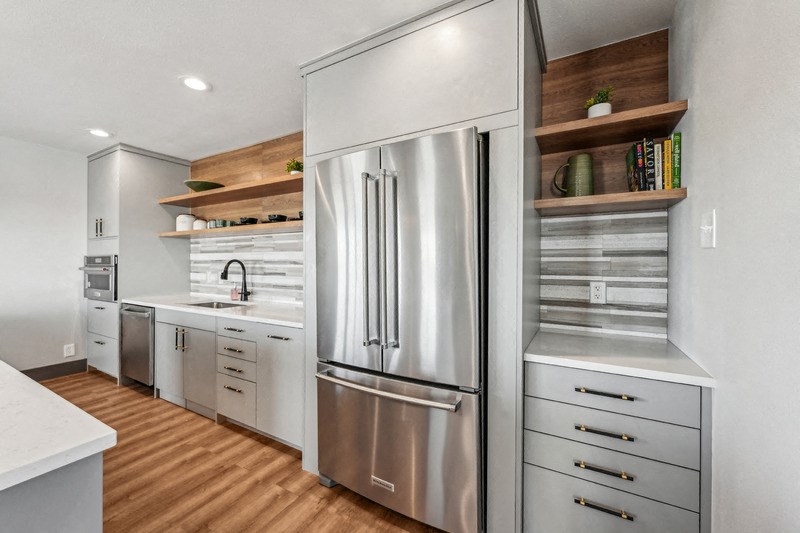 A modern kitchen with a stainless steel refrigerator and wooden shelves. at The Lex At Lowry, Denver