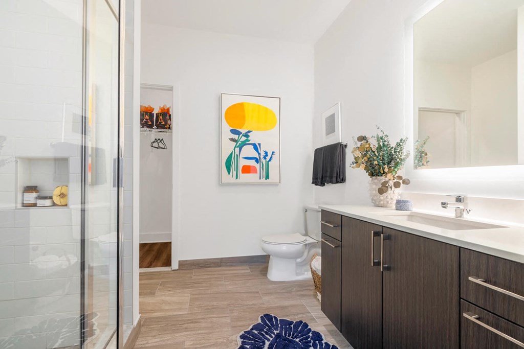 A bathroom with a toilet, sink, and a painting on the wall.at The Vale at the Parks, Washington District of Columbia  