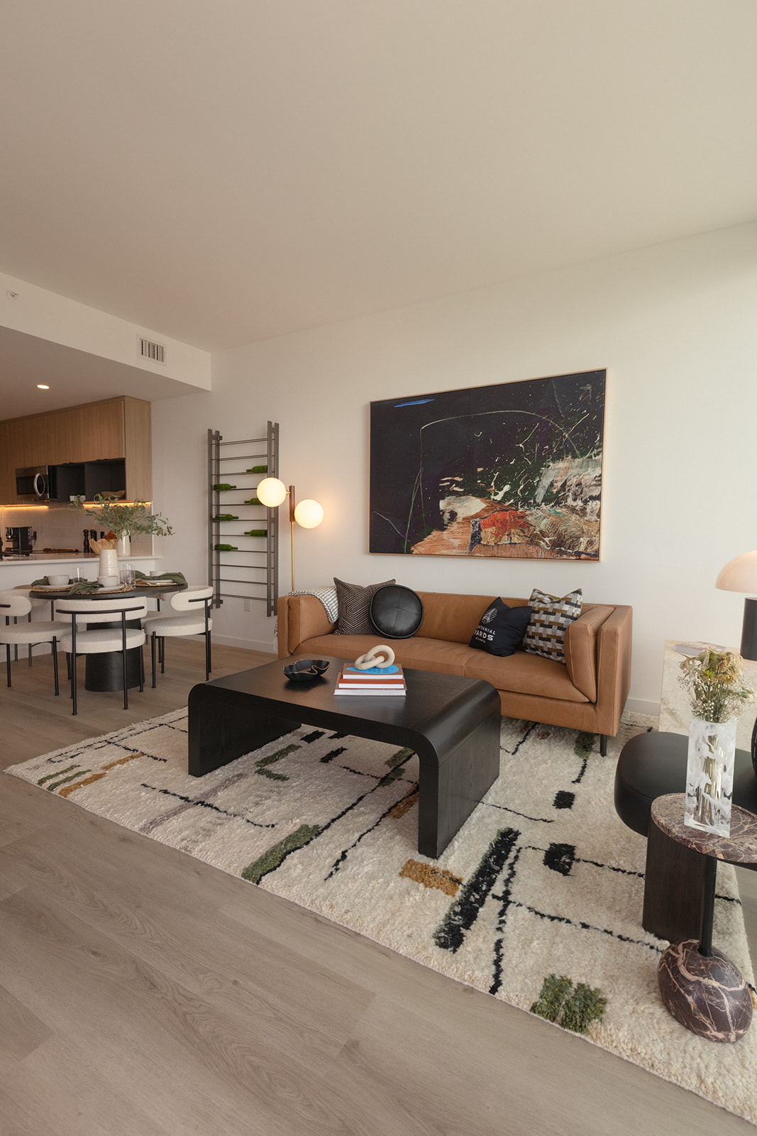 A modern living room with a brown couch and a large painting on the wall.