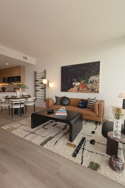 A modern living room with a brown couch and a large painting on the wall.
