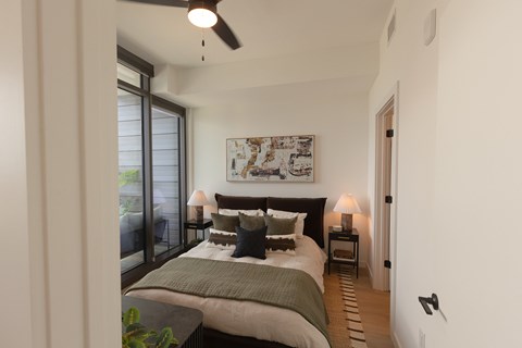 A bedroom with a bed, nightstands, and a ceiling fan.