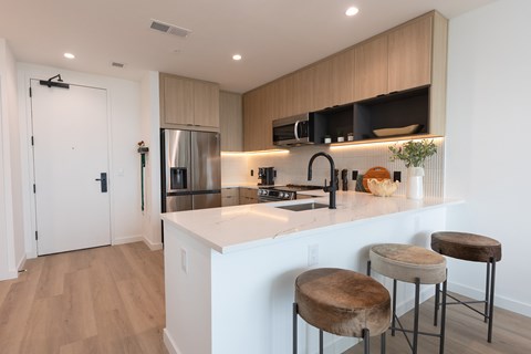 A kitchen with a white counter top and bar stools.