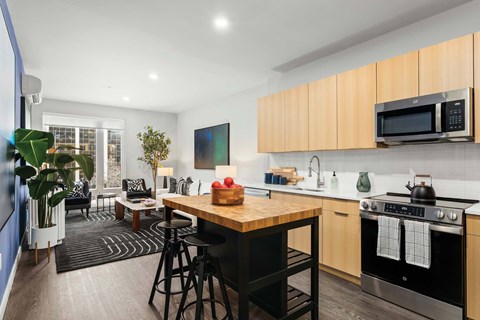 A modern kitchen with a wooden table and black stools.