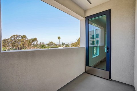 A modern house with a glass door and a view of trees outside.