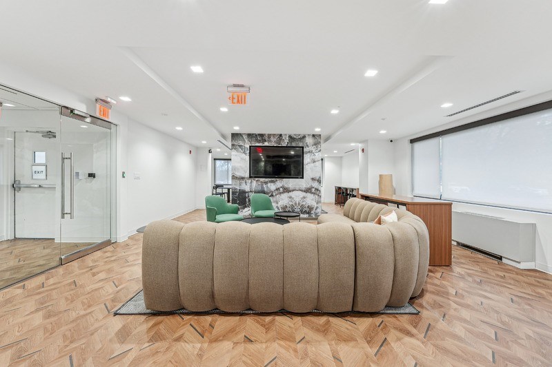 A room with a large round couch and a television.