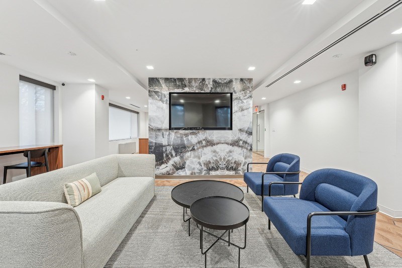A living room with a grey couch, a blue chair, and a black table.