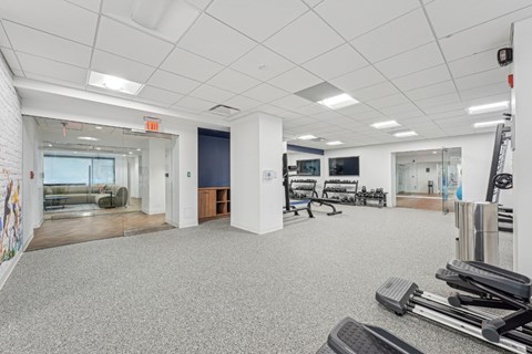 A gym with a variety of equipment including treadmills, weights and exercise machines.