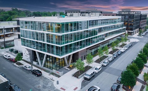 A modern glass building with cars parked in front.