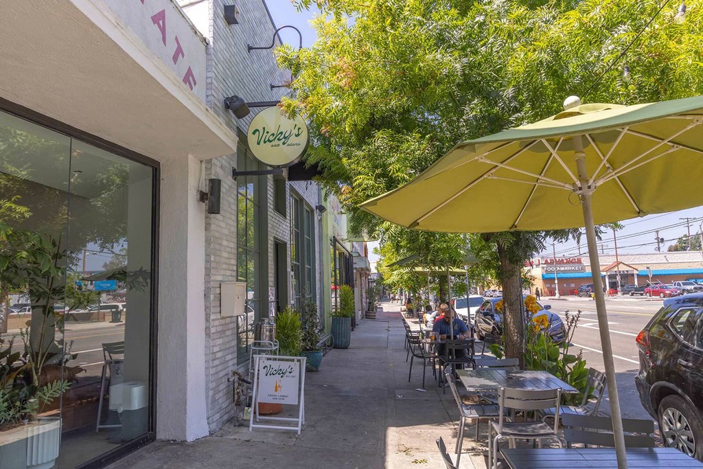 A yellow umbrella is on a table outside of a restaurant.