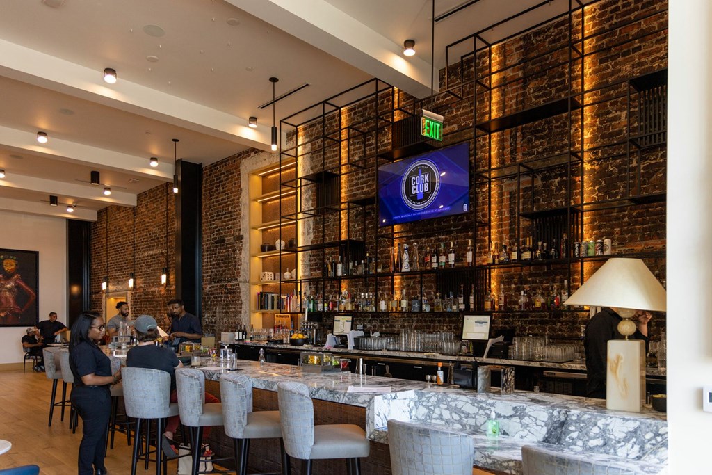 A bar with people sitting at the bar and a TV screen on the wall.