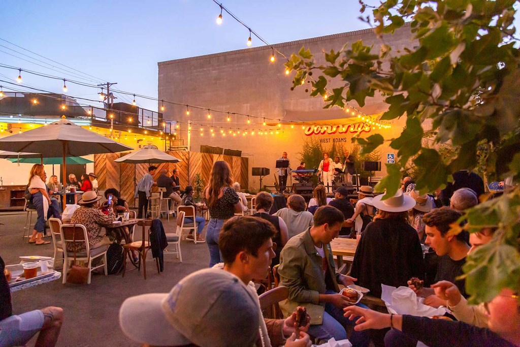 A group of people are sitting at tables outside a restaurant.