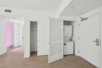 A white room with a pink door and a white fridge.