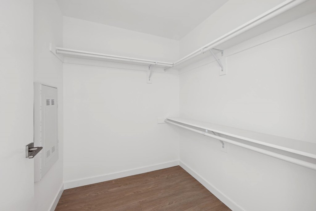A white room with a door and a shelf.