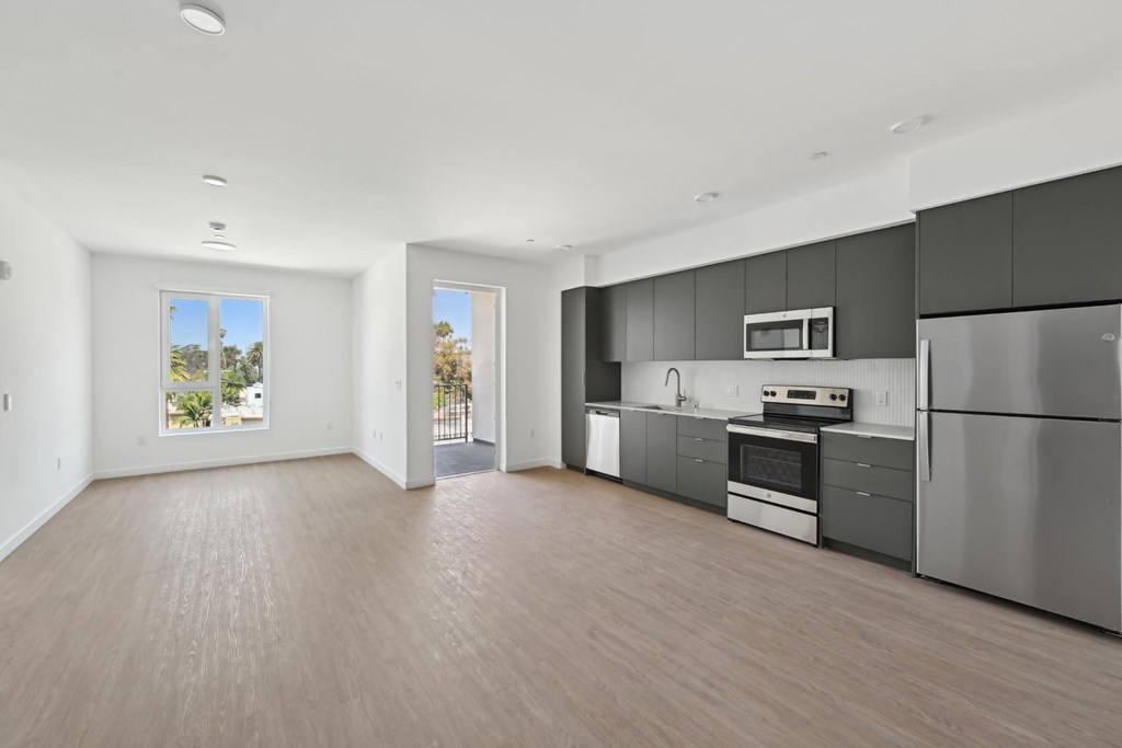A modern kitchen with stainless steel appliances and wooden flooring.