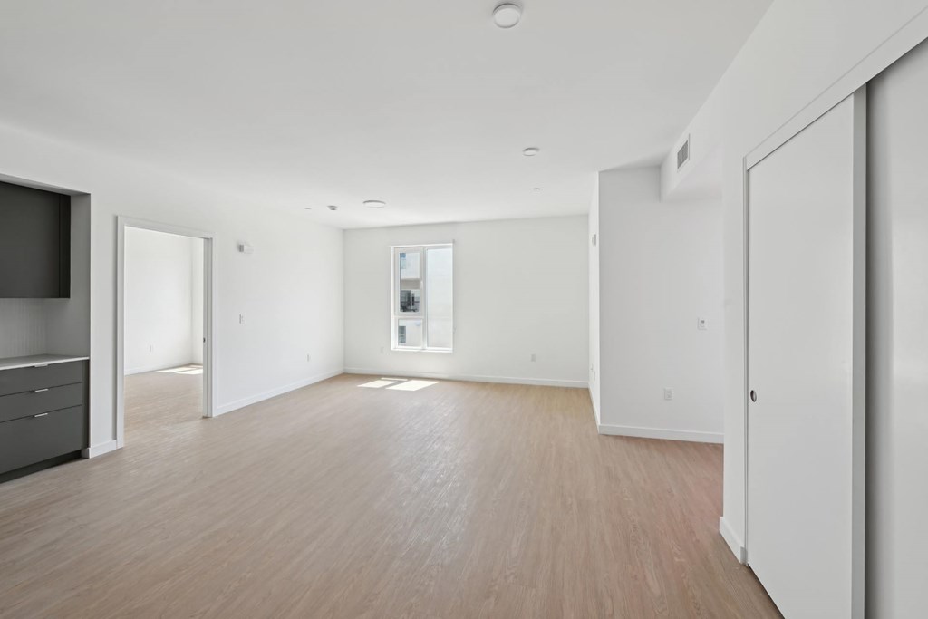 A spacious room with wooden flooring and white walls.
