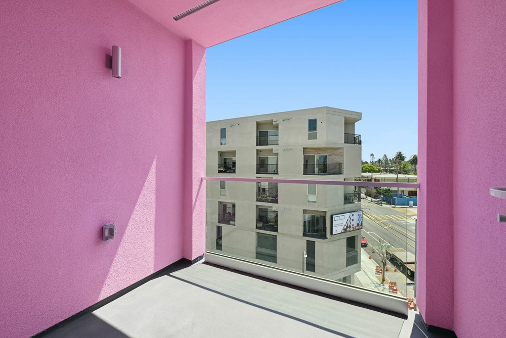 A pink wall with a window overlooking a building.