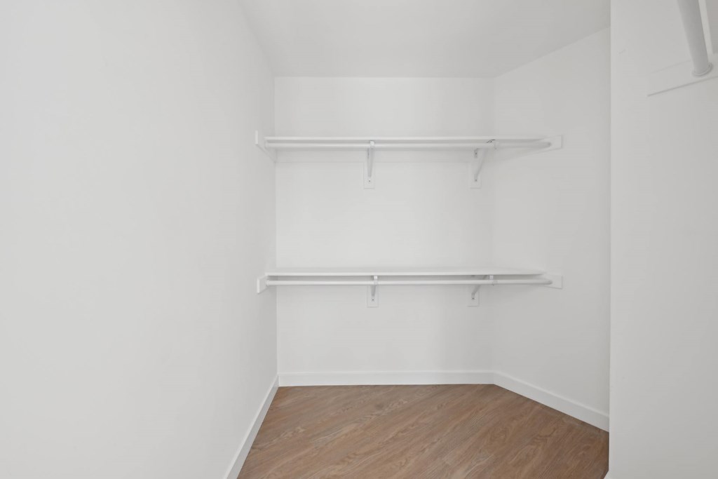 A white room with two shelves and wooden flooring.