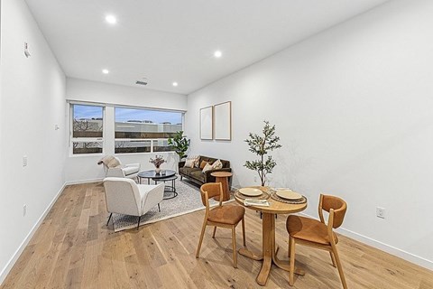 A dining room with a table set for two and a couch.