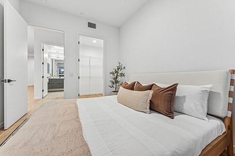A bedroom with a large bed and a small tree.