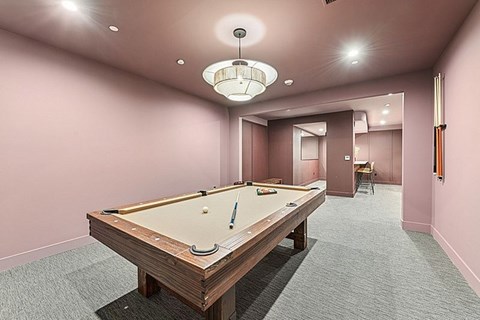 A pool table in a room with pink walls.
