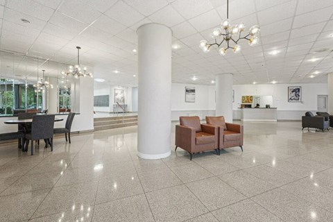 A spacious lobby with a white column, chairs, and a chandelier.