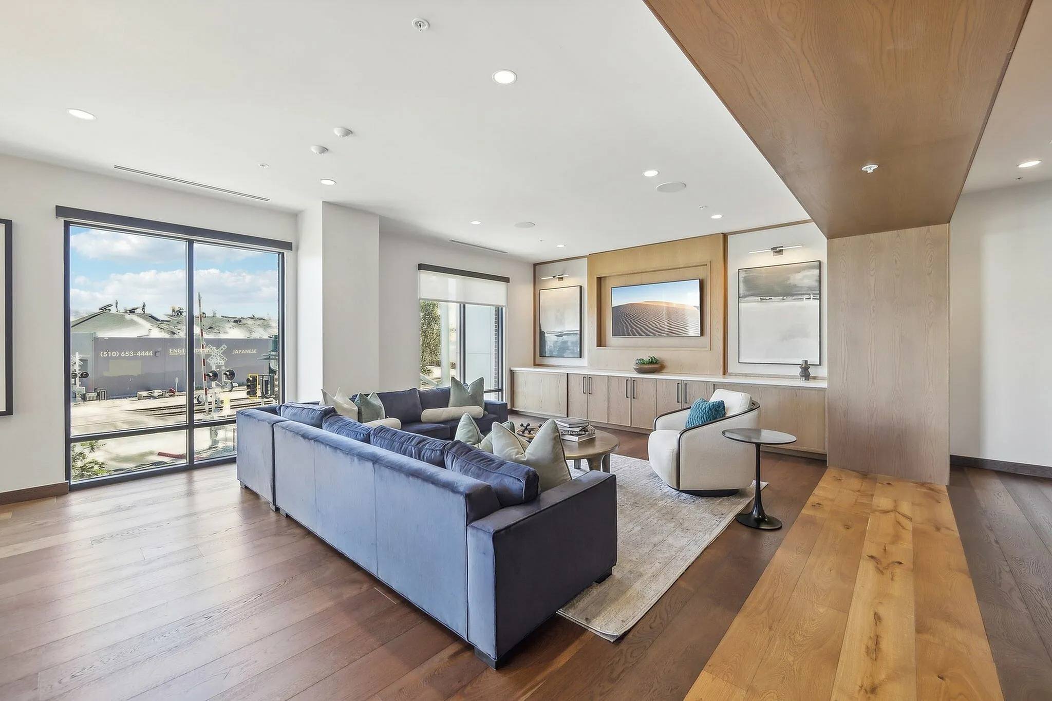 A modern living room with a grey sofa and wooden flooring.