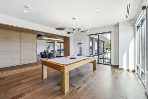 A room with a long wooden table and a pool table in the middle.