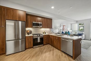 Kitchen with wooden cabinetry and refrigerator at Bayview Apartments, Emeryville, CA