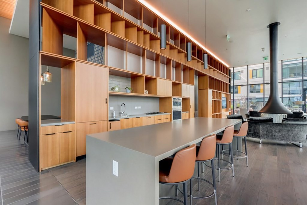 A modern kitchen with a long island and chairs.at Channel House, Oakland, CA 94607