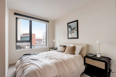 A bedroom with a large bed and a window overlooking a cityscape.