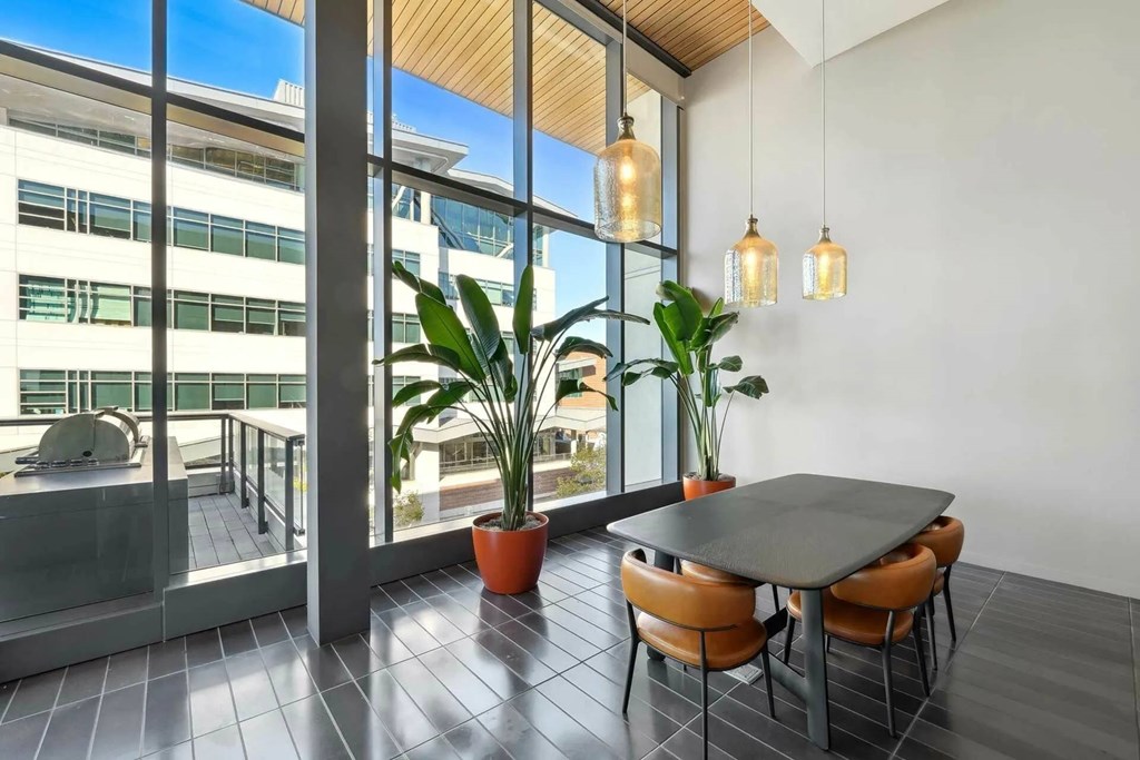 A modern dining area with a table, chairs, and potted plants.at Channel House, Oakland, CA
