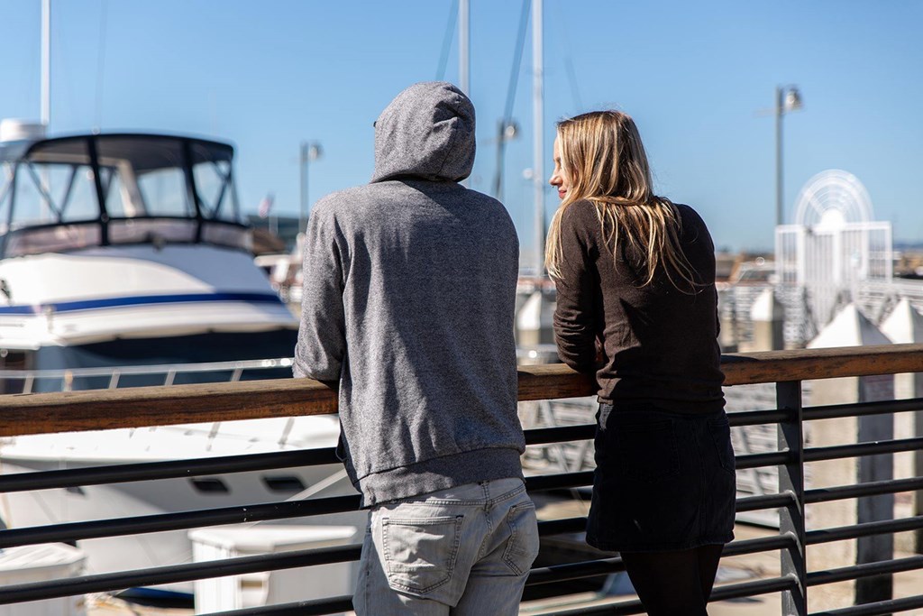 A man and a woman are standing on a dock looking at boats.at Channel House, Oakland