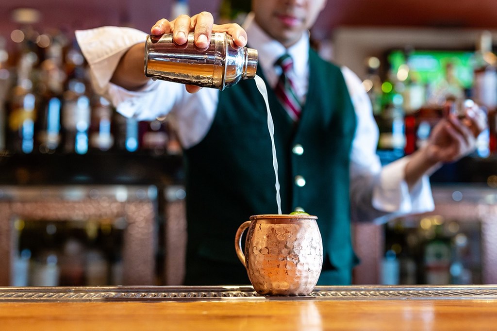 A bartender pouring a drink into a cup.at Channel House, Oakland, CA 94607