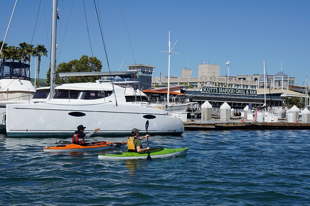 Two people kayaking in the water near a dock.at Channel House, Oakland