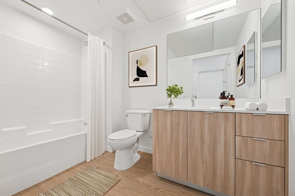 A white bathroom with a toilet, sink, and bathtub at Coro Apartments, California