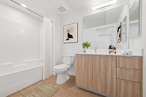 A white bathroom with a toilet, sink, and bathtub at Coro Apartments, California